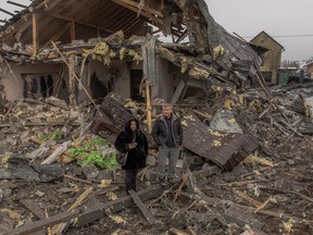 Local residents stand next to a destroyed house