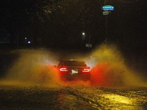 A car drives on a flooded street in Philadelphia early Monday, Dec. 18, 2023.