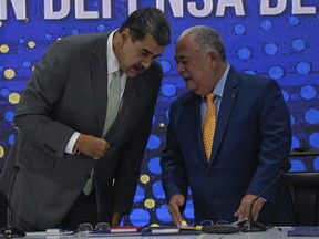 Venezuela's President Nicolas Maduro, left, speaks with National Electoral Council President Elvis Hidrobo Amoroso during the notification ceremony for the referendum about the future of a disputed territory with Guyana, in Caracas, Venezuela, Monday, Dec. 4, 2023.
