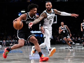 Dennis Smith Jr. of the Brooklyn Nets is defended by Damian Lillard of the Milwaukee Bucks.