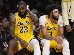 Los Angeles Lakers' LeBron James, left, and Anthony Davis sit on the bench.