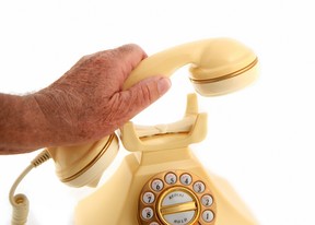 Man holds receiver of vintage landline telephone.
