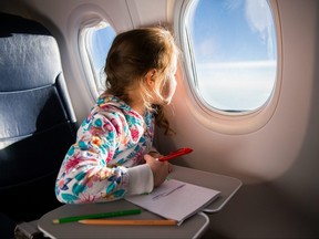 Child drawing picture with crayons in airplane.