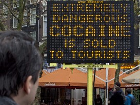 A man looks at a sign that warns of extremely dangerous cocaine being sold to tourists at Rembrandtplein square in Amsterdam, Netherlands, Thursday, Nov. 27, 2014. (AP Photo/Peter Dejong)
