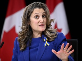 Chrystia Freeland speaks with Canadian flags in the background
