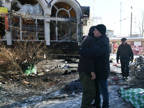 Two men embrace each other as they stand next to a body of a person, killed as a result of a missile strike in Donetsk on Jan. 21, 2024, amid the ongoing Russian-Ukrainian conflict.