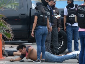 Ecuadorean police officers guard arrested suspects