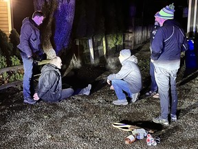 A group gather around a suspect on the ground with their hands behind their back