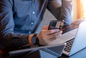 Businessman using a smartphone and laptop while working in the cafe.