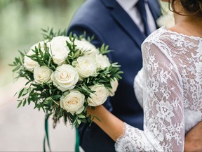 Closeup of brides bouquet as she hugs groom outside on their wedding day