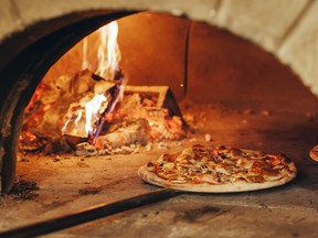 Pizza is cooked in a wood-fired oven.