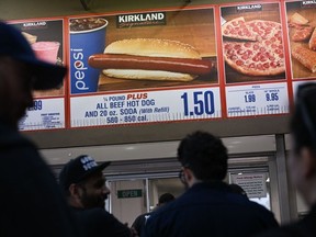 Customers wait in line to order below signage for the Costco Kirkland Signature $1.50 hot dog and soda combo