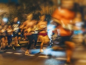 Large blurred group of runners on street at night.