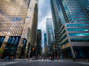 Few people at an intersection amid modern skyscrapers in downtown Toronto