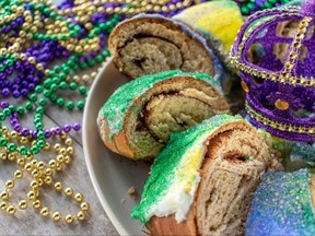 Sliced Mardi Gras king cake surrounded by colorful beads