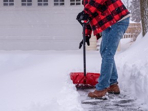 A man shovels the driveway after a heavy snowfall.