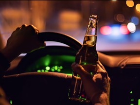 Man drink beer while driving at night in the city. Dangerously driving