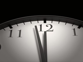 Round black and white clock with both the hour hand and minute hand almost pointing to 12 o'clock. Illustration of the concept of due date, deadline, countdown and doomsday