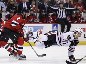 Chicago Blackhawks centre Connor Bedard falls to the ice after being checked by New Jersey Devils defenceman Brendan Smith (2) during the first period of an NHL hockey game Friday, Jan. 5, 2024, in Newark, N.J.