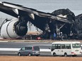 Officials look at the burnt wreckage of a Japan Airlines plane