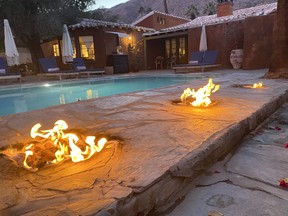 Fire pits line the edge of one of the pools as the sun goes down at the Korakia in Palm Springs, California.