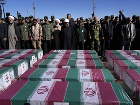 People pray over the flag-draped coffins of victims of Wednesday's bomb explosion during their funeral ceremony in the city of Kerman about 820 km southeast of the capital Tehran, Iran, Friday, Jan. 5, 2024.