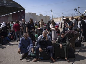 Palestinians wait to cross into Egypt at the Rafah border crossing in the Gaza Strip oFatima Shbair, Filen Monday, Oct.16, 2023.