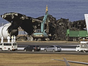 A removal work, rear, is underway at the site of a planes collision at Haneda airport in Tokyo, on Jan. 5, 2024.