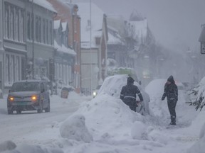 People attempt to clear the snow off a vehicle, in Kristiansand