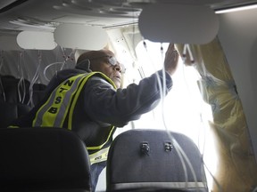 In this photo released by the National Transportation Safety Board, NTSB Investigator-in-Charge John Lovell examines the fuselage plug area of Alaska Airlines Flight 1282 on Sunday, Jan. 7, 2024, in Portland, Ore.