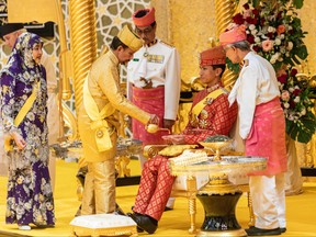 This photograph taken on Jan. 10, 2024 shows Brunei's Sultan Hassanal Bolkiah (second from left) pouring scented oil on the hands of Prince Abdul Mateen during the royal powdering ceremony at Istana Nurul Iman, ahead of his wedding to Anisha Rosnah, in Bandar Seri Begawan, as Queen Raja Isteri Pengiran Anak Hajah Saleha (left) looks on.