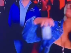 In a screenshot from video posted to X, a woman, far right, pulls up her top after exposing her breast in video that was shown during the Sugar Bowl broadcast on ESPN on Jan. 1, 2024.