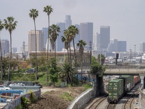 Los Angeles skyline is seen above a train rolling near the Union Pacific LATC Intermodal Terminal on Tuesday, April 25, 2023, in Los Angeles.