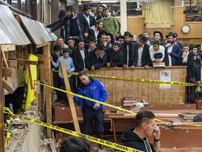 Hasidic Jewish students observe as law enforcement establishes a perimeter around a breached wall in the synagogue that led to a tunnel dug by students, Monday, Jan. 8, 2024, in New York.