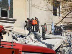 Security and emergency personnel search the rubble of a building