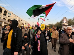 People wave flags and hold placards with anti-US and anti-Israel slogans on Jan. 5, 2024 in Tehran, during the funeral of Faezeh Rahimi, one of the victims killed in the southen Iranian city of Kerman on Jan. 3 in twin blasts during a commemmoration marking the anniversary of the killing of Revolutionary Guards general Qasem Soleimani.