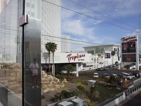 A person, reflected in glass, walks near the Tropicana Las Vegas