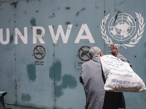 This file photo taken on July 31, 2018 shows a Palestinian man standing in front of the emblem of the UN Relief and Works Agency for Palestine Refugees in the Near East (UNRWA) outside the agency's offices in Gaza City.