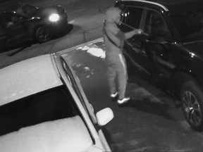 A person wearing a hood by a carduring an act suspected vandalism