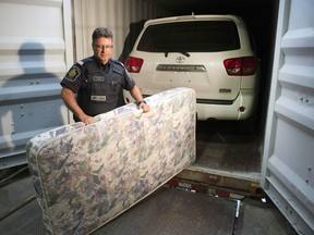 CBSA Superintendent Jean-Francois Rainville removes a mattress that was used to hide a stolen Toyota Sequoia in a container at a news conference in Montreal, Thursday, July 17, 2014.