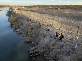 immigrants walk along the bank of the Rio Grande