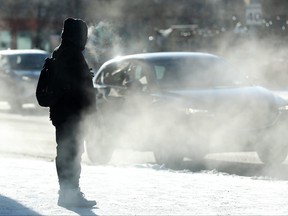A pedestrian is shrouded in car exhaust while making their way through the bitter cold in downtown Edmonton, Saturday, Jan. 13, 2024.