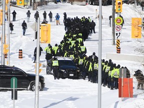 A judge's declaration that the federal government was unjustified in using Canada's emergency legislation to quell a weeks-long protest in Ottawa has left the administrator of a downtown church feeling the court disregarded infringements of her rights. A lineup of police officers assemble on Colonel By Drive near the truck blockade in Ottawa, on Friday, Feb. 18, 2022.