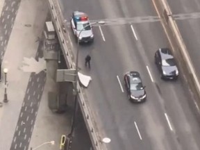 Screenshot of Toronto Police officer on Gardiner Expressway to retrieve table and mattress in right lane.