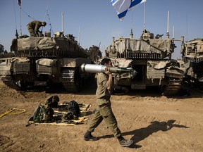 An Israeli soldier carries a tank shell