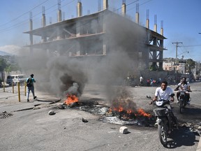 A motorcyclist passes by burning tires in Haiti