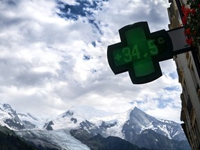 This photograph taken on July 11, 2023, shows a pharmacy sign indicating 34,5 degrees celsius with the Mont-Blanc in the background during a heat wave, in Chamonix.