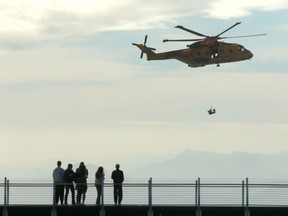 People look on as the AgustaWestland CH-149 Cormorant helicopter demonstrates a search and rescue operation during the Defence on the Dock at the Ogden Point Breakwater District in Victoria, Sunday, Sept. 17, 2023. Officials have confirmed that a helicopter crashed on Terrace in B.C. Monday afternoon.