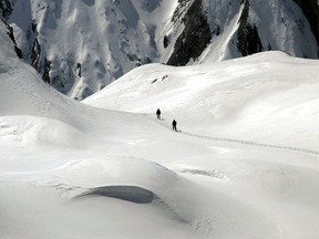 FILE - Two mountain hikers are dwarfed by the winter landscape of the Formazza Valley, northern Italy, on April 11, 2004. Italy's alpine rescue service says two persons who were hiking with snowshoes have died after being struck by an avalanche. A spokesperson for the alpine rescuers said the avalanche occurred in early afternoon on Sunday at the 2,200-meter (7,200-foot) level in the Formazza valley in the Piedmont region near Switzerland.