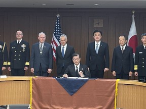 Japanese and U.S. military officials and U.S. Ambassador to Japan Rahm Emanuel, fourth left, and Japanese Defense Minister Minoru Kihara, third right, stand behind a defense equipment procurement official as he signs a document for the Tomahawk purchase deal at the Japanese Defense Ministry, in Tokyo, Thursday, Jan. 18, 2023. Japan has signed a deal with the United States to purchase up to 400 Tomahawk cruise missiles as part of its ongoing military buildup in response to increased regional threats. U.S. Ambassador to Japan Rahm Emanuel attended a signing event at Japan's Defense Ministry on Thursday.